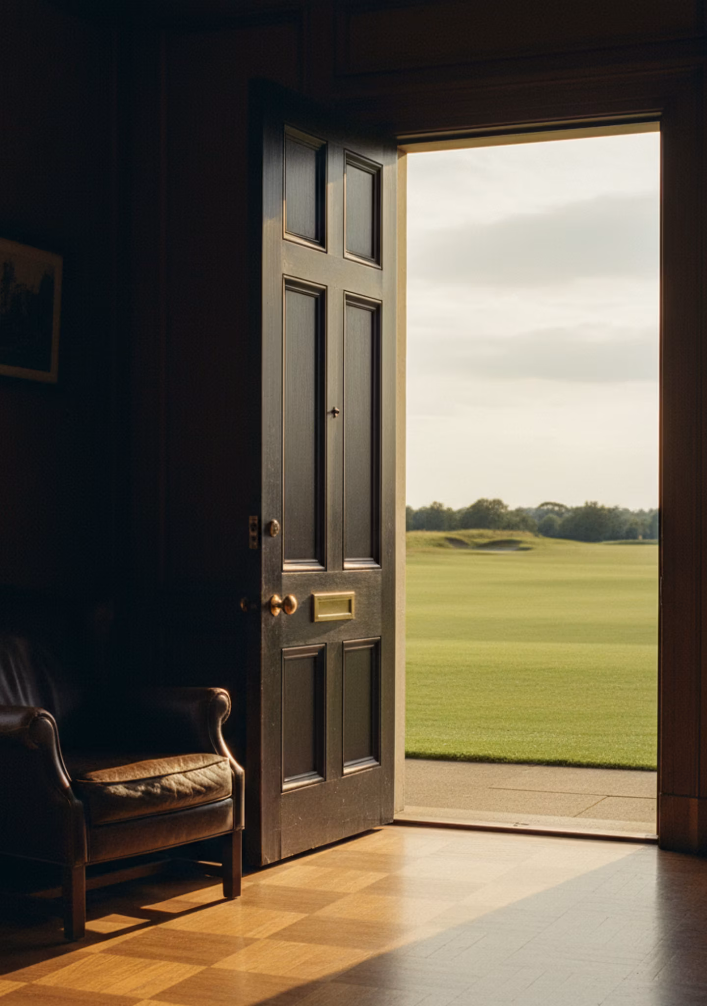 A clubhouse interior threshold opening onto a fairway in late afternoon light
